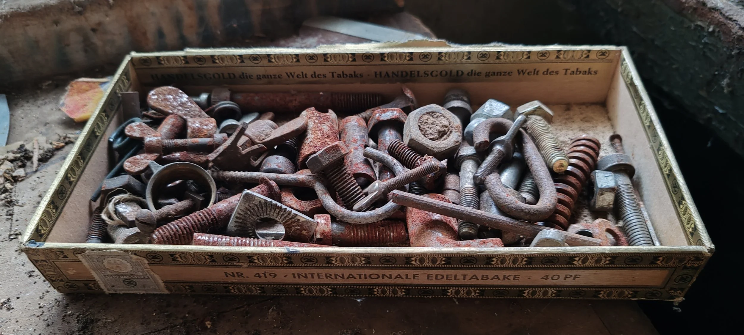 Alte, rostige Schrauben und Muttern in einer Zigarettenschachtel.