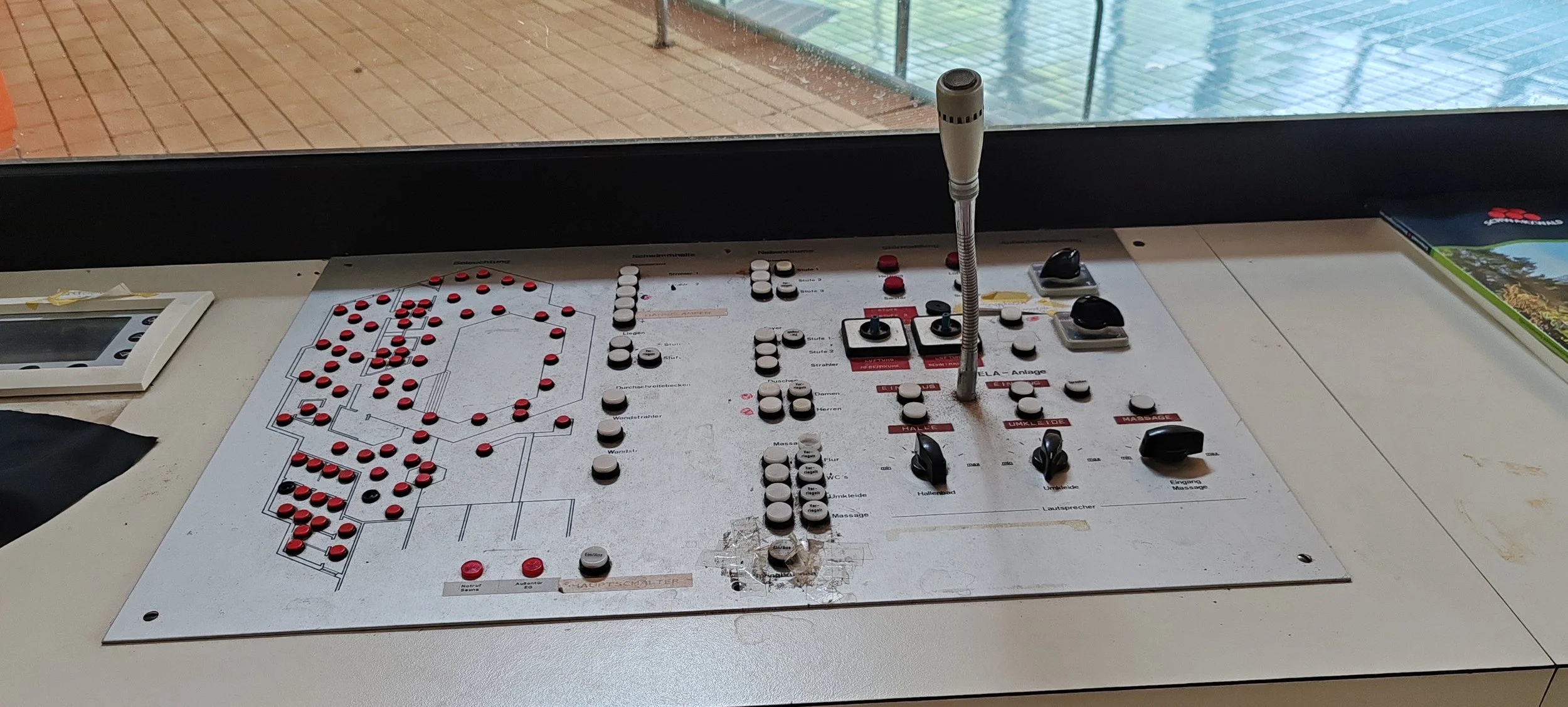 Brandstellplatz mit Notrufknopf, Lautsprechern, Schaltern und Kontrollleuchten, auf einer Tafel an einer Bushaltestelle.