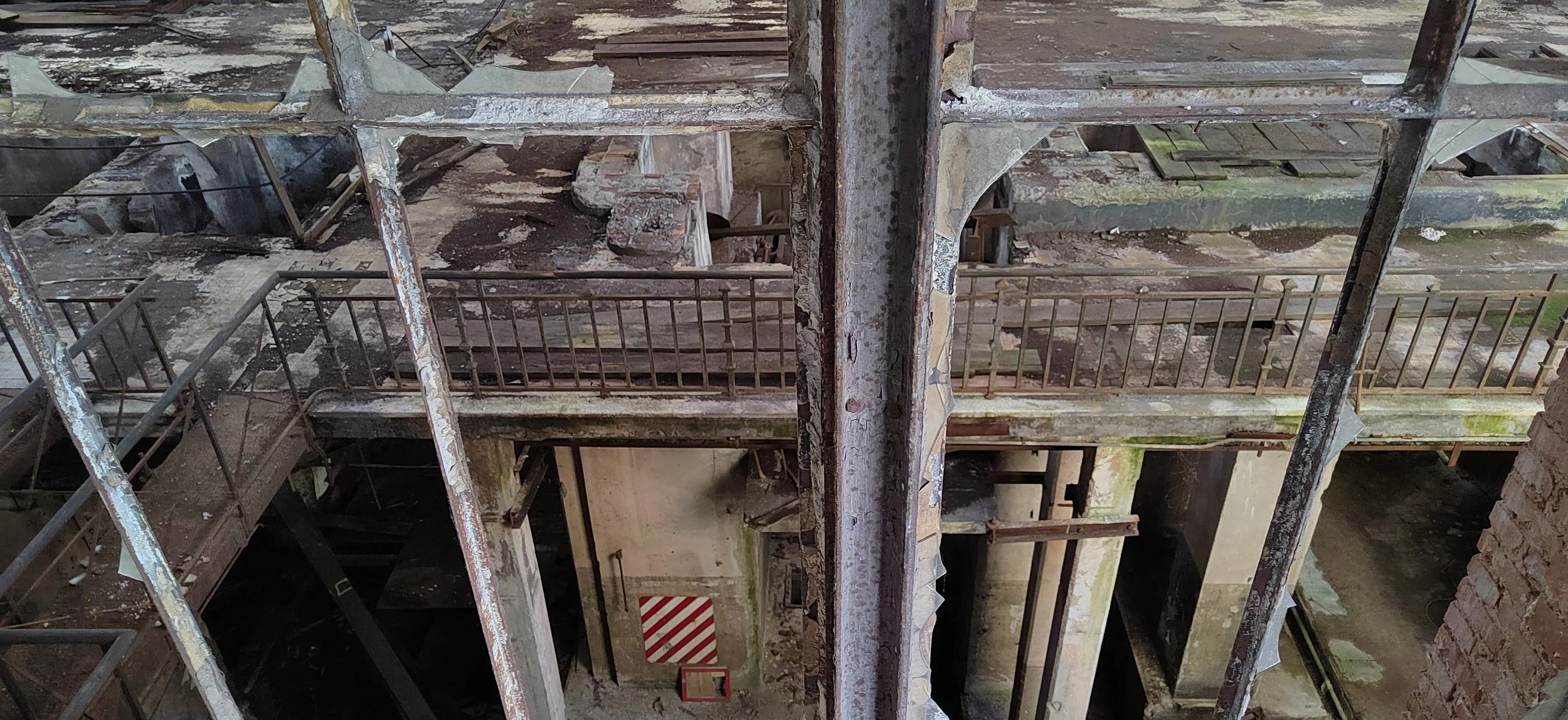 Verfallene und beschädigte Gebäudestruktur mit rostigen Metallgeländern, zerbröckeltem Mauerwerk und schrägen Ebenen.