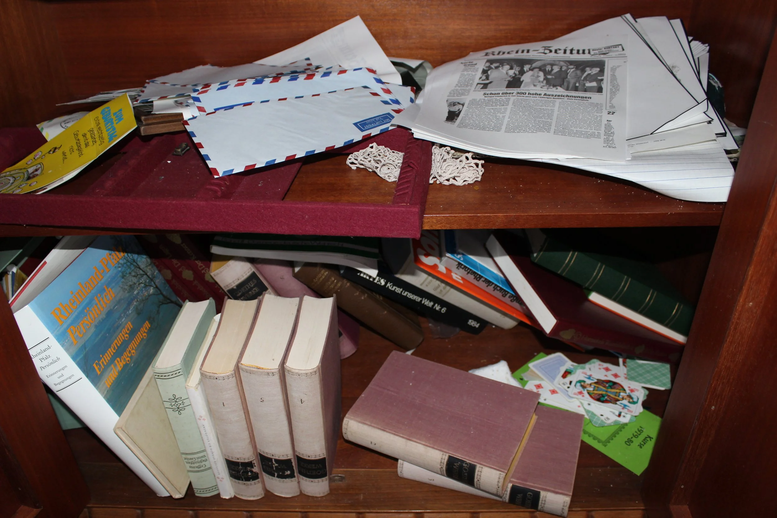 Verschmutzter, unordentlicher Bücherregal mit Büchern, Zeitungen, Briefumschlägen, Karten und anderen Gegenständen