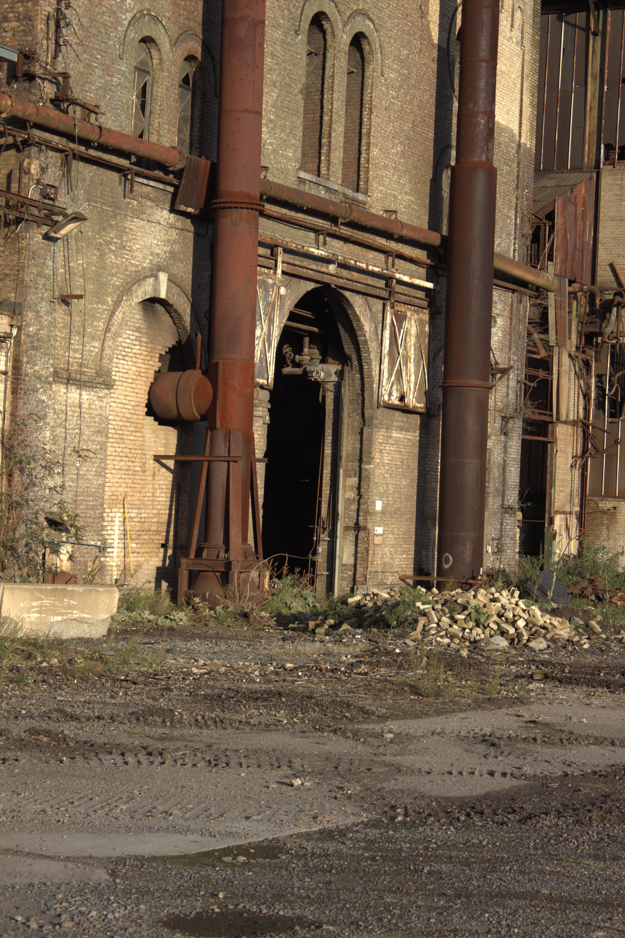Ein verlassener, alter Industriebau mit rostigen Rohren und bröckelnden Backsteinmauern.