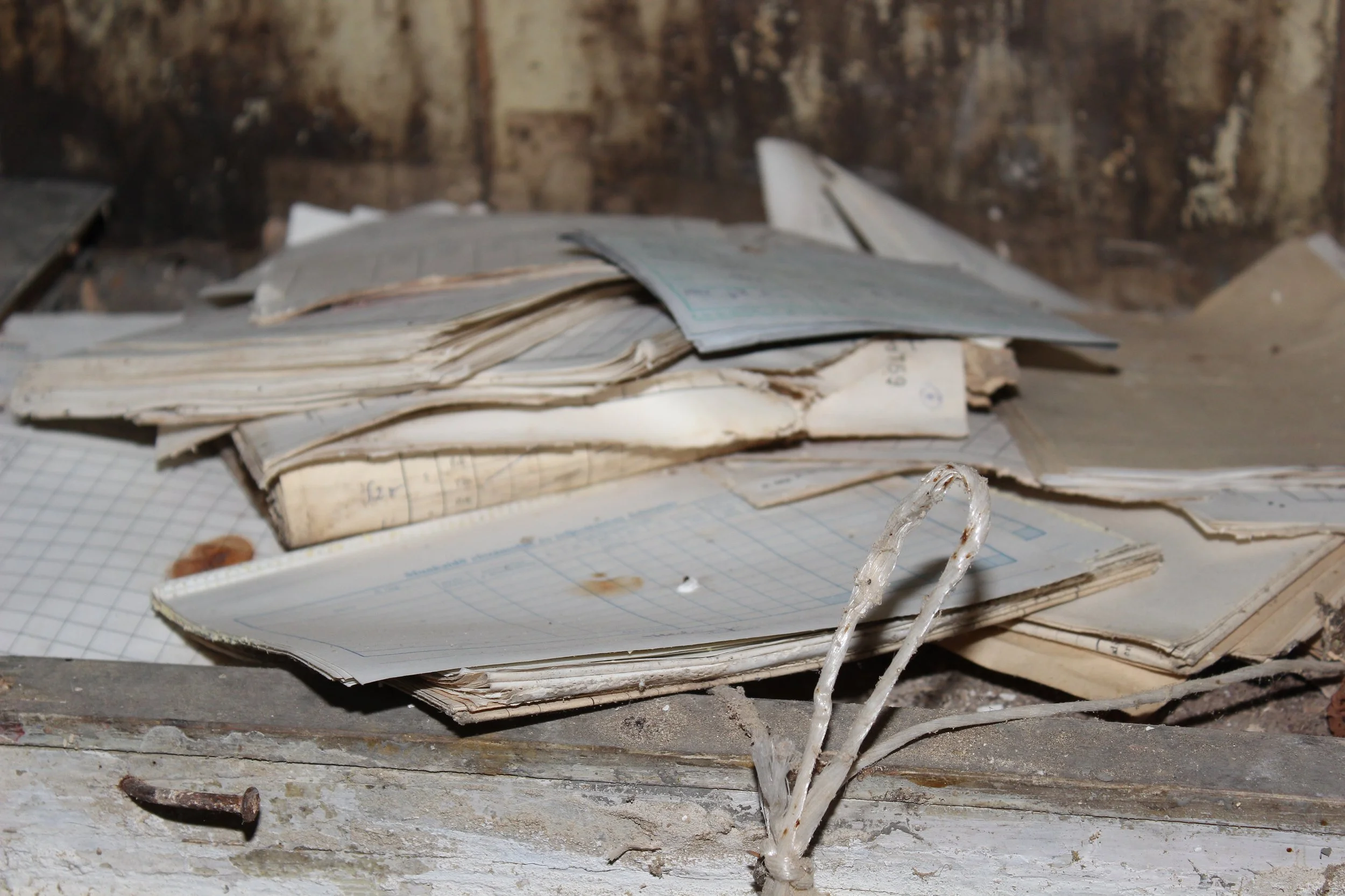 Alte, zerknitterte Notiz- und Schreibblätter liegen auf einem alten Tisch, im Hintergrund eine Holzwand.