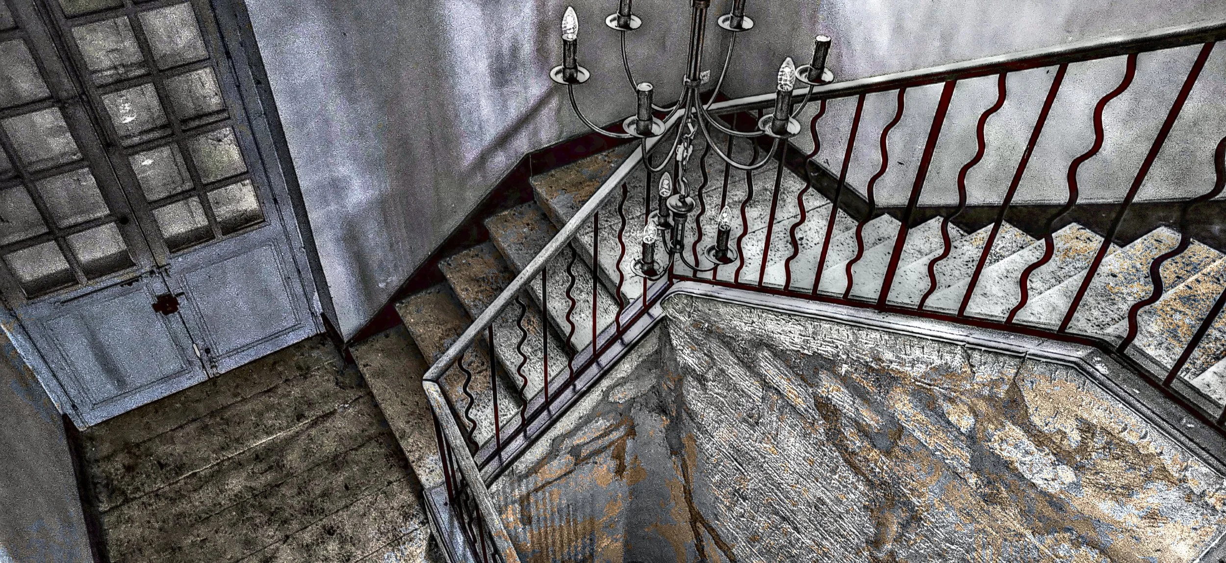 Stufen und Eisenbahnstahlhandlauf in einem alten, verfallenen Treppenhaus mit einer Hängeleuchte.