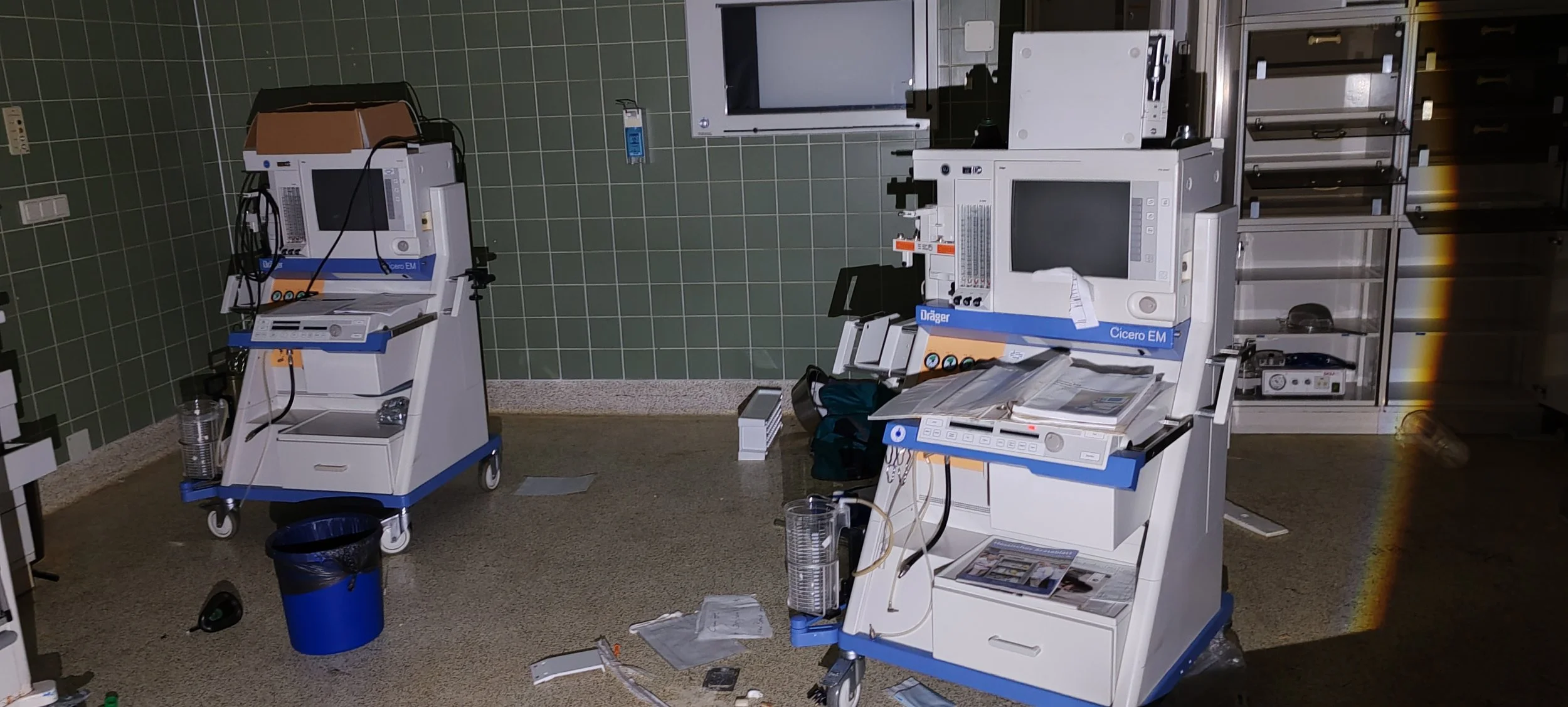 Leere medizinische Geräte und Schreibtische in einem Krankenhauszimmer, chaosartige Unordnung mit Papieren und medizinischem Zubehör