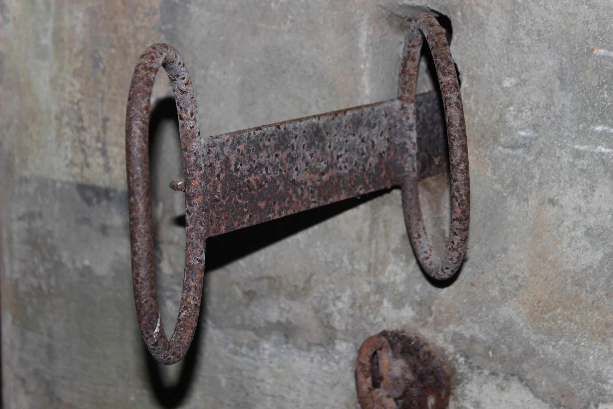 Ein altes, rostiges Metallmolekül an einer Steinmauer befestigt.