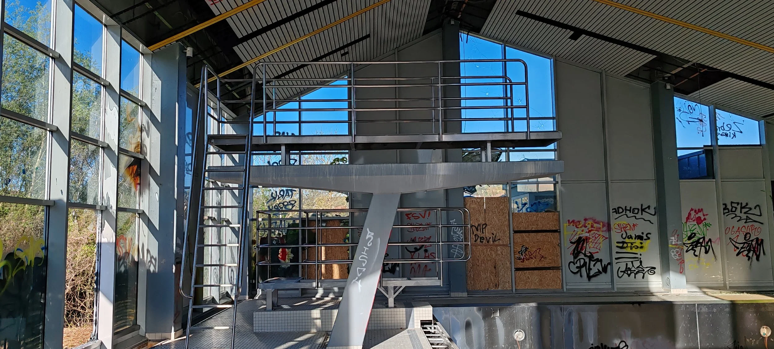 Verfallene, verunstaltete moderne Gebäude mit viel Graffiti, zerbrochenen Fenstern und einem Dach, das teilweise offen ist. Innenraum ist beschädigt und verfallen.