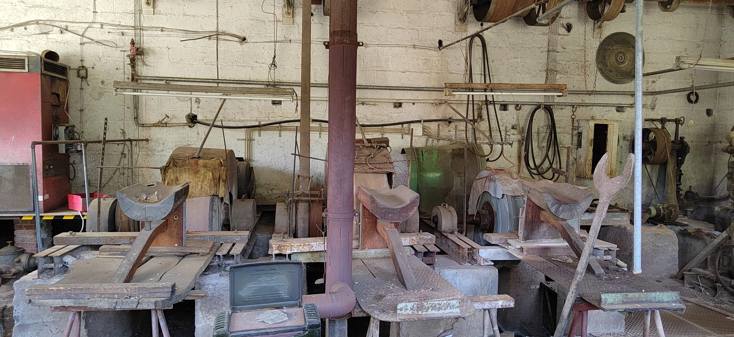 Alter Werkstattraum mit verstaubten und rostigen Maschinen, Werkzeugen und Metallteilen.