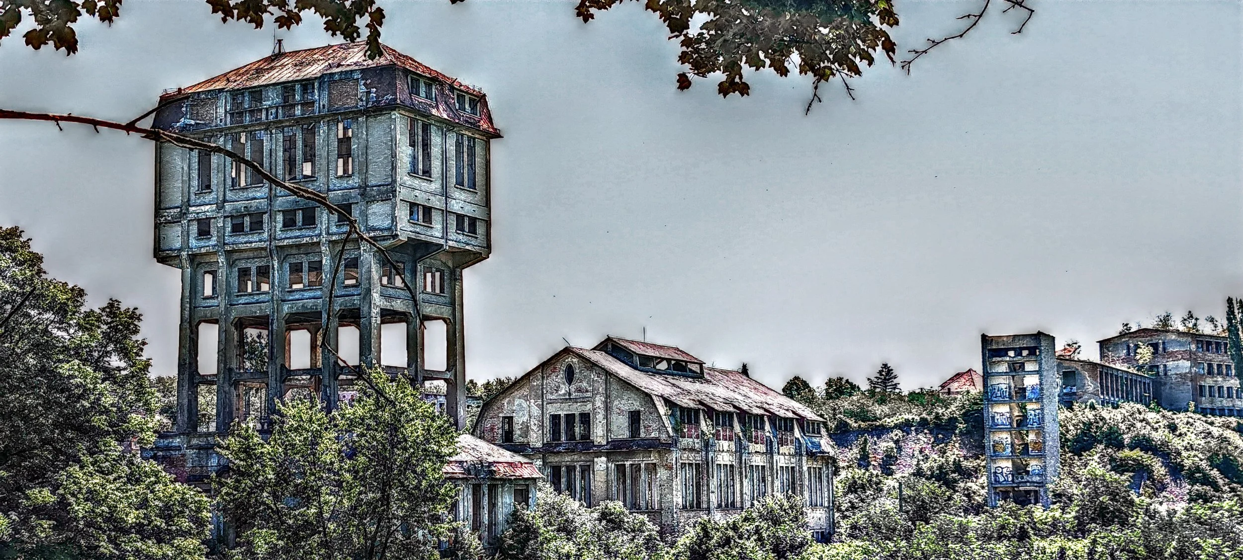 Verlassene alte Gebäude in einer grünen Umgebung mit Bäumen und Himmel im Hintergrund.