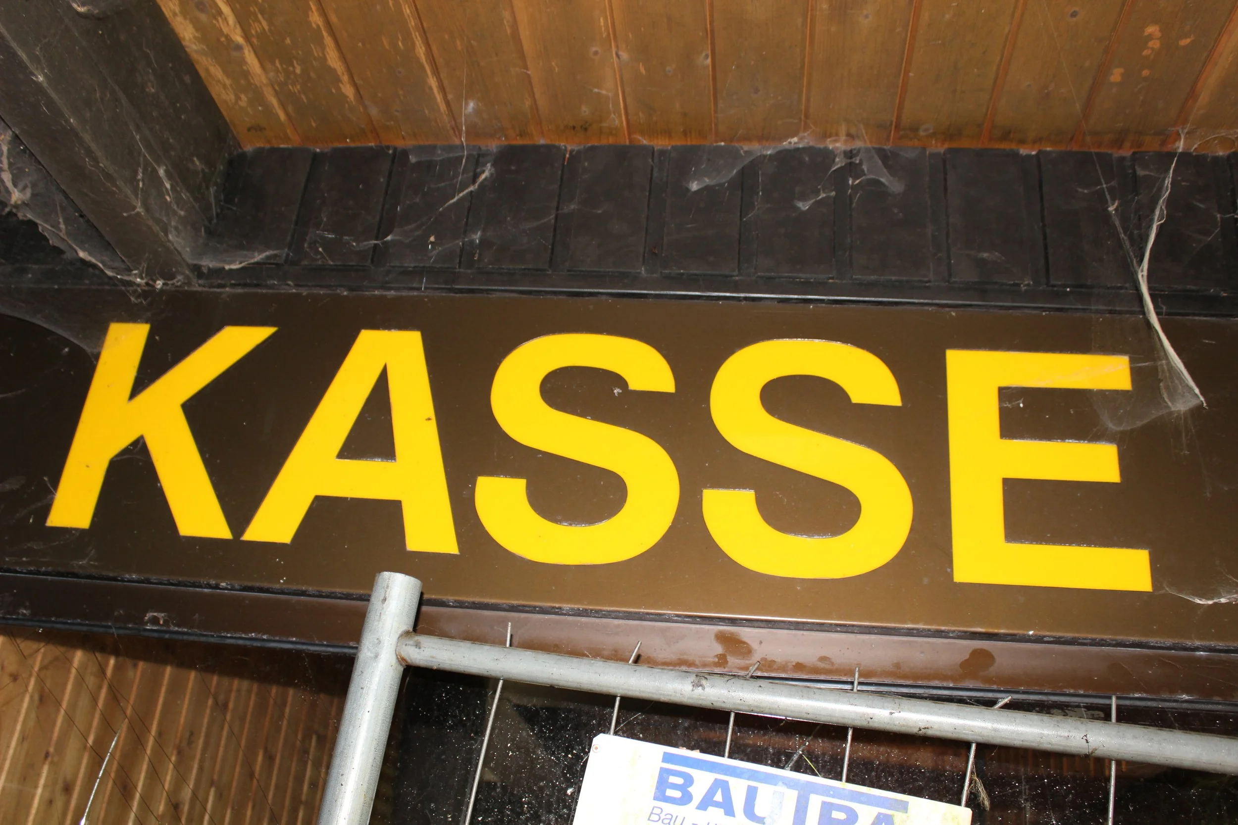 Ein schwarzes Schild mit großen gelben Buchstaben, auf dem das Wort "KASSE" steht.