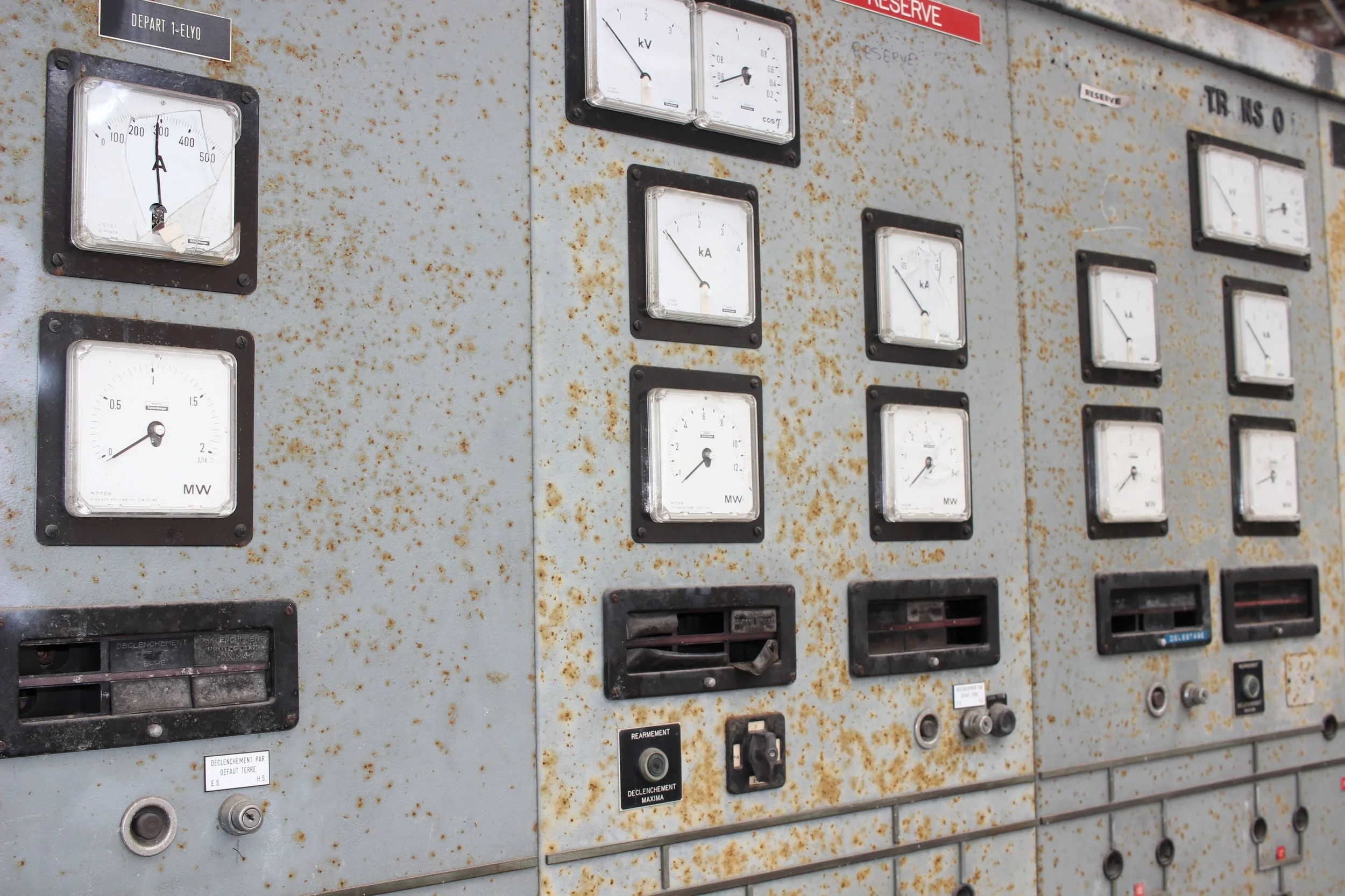 Verrosteter elektrischer Verteilerkasten mit mehreren analogen Messgeräten und Schaltern