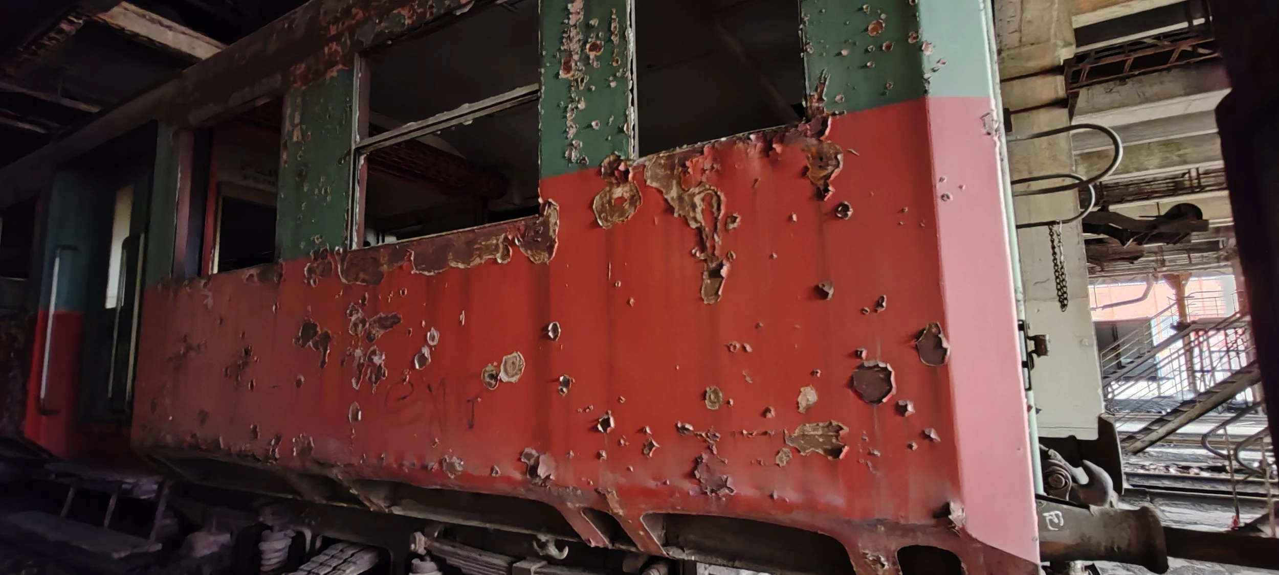 Alte, verrostete und beschädigte Eisenbahnwagen in einem verwaisten Bahnhofsgebäude.