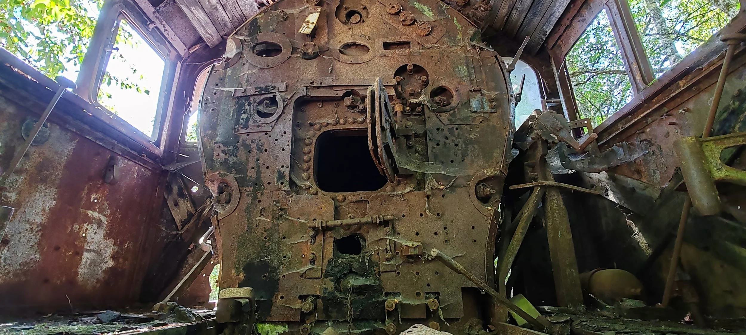 Das Innere eines verrosteten und verfallenen Flugzeugs mit sichtbaren Kabeln, Metallteilen und offenen Fenster.