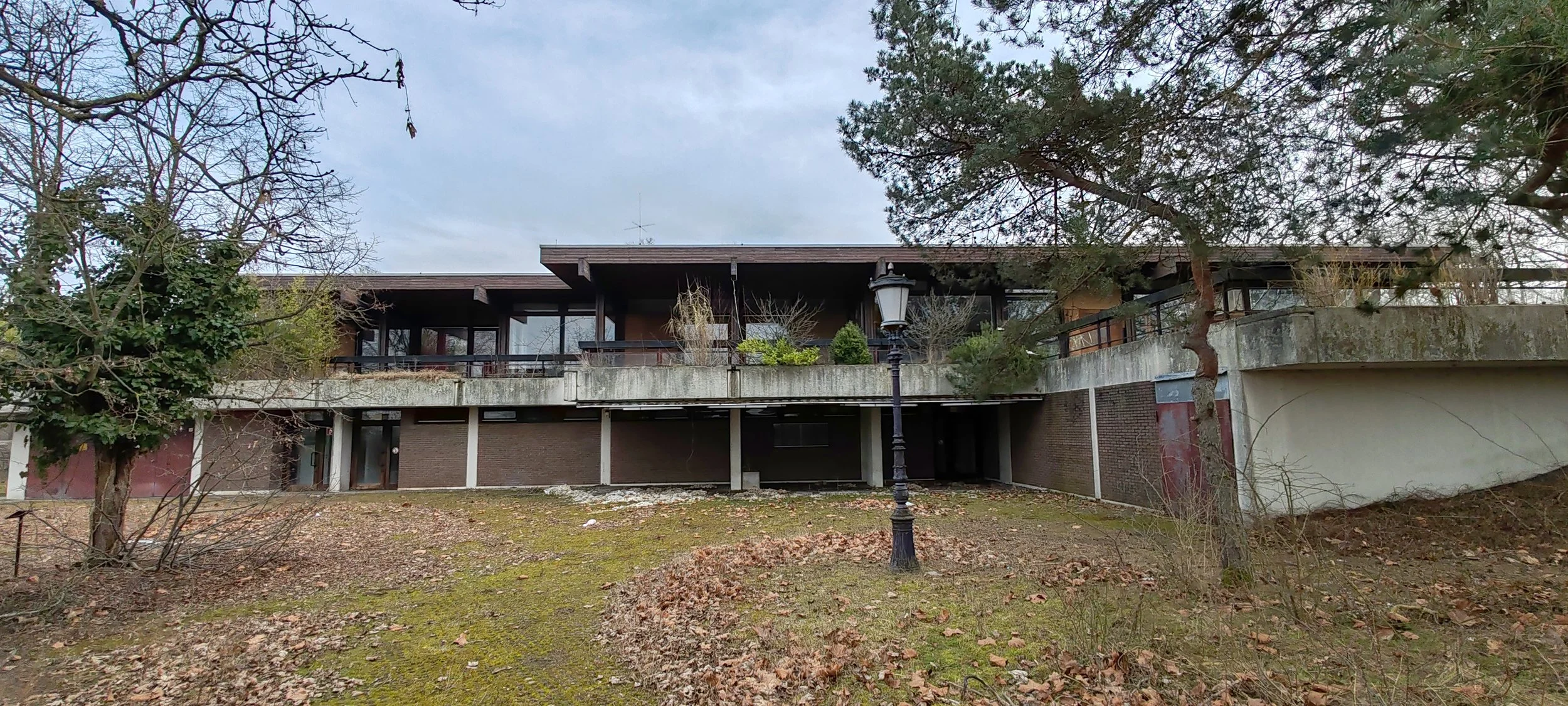 Mehrstöckiges Haus mit Balkon im Garten, umgeben von Bäumen, im Winter