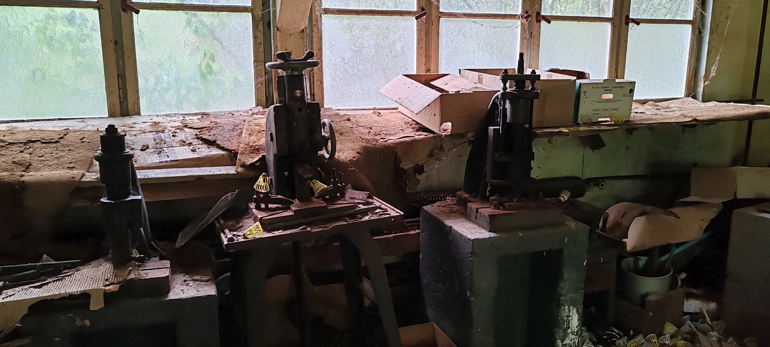 Alte Werkbank mit Werkzeugen und Maschinen in einer Werkstatt, beleuchtet von durchscheintem Tageslicht durch die Fenster im Hintergrund.