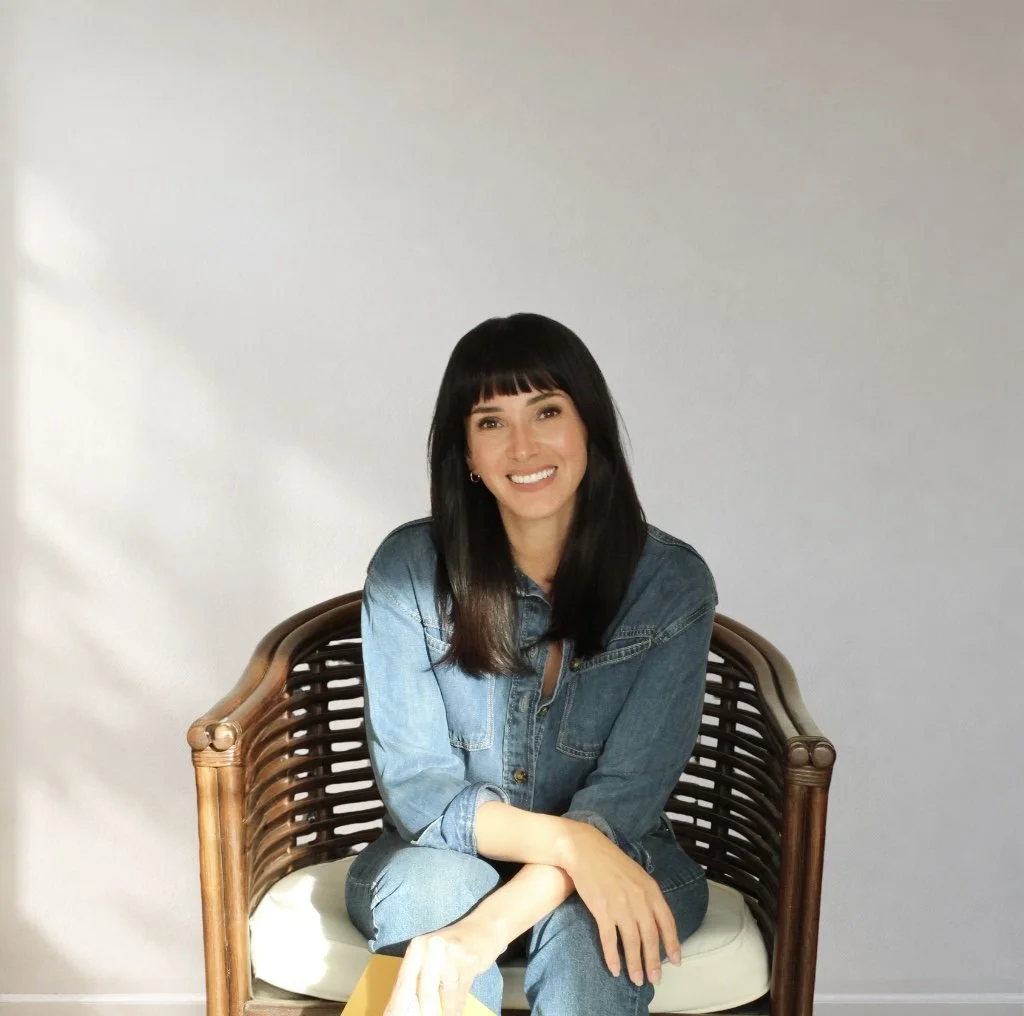 Maegan Jones, LCSW, smiling in a denim shirt, seated in a woven chair