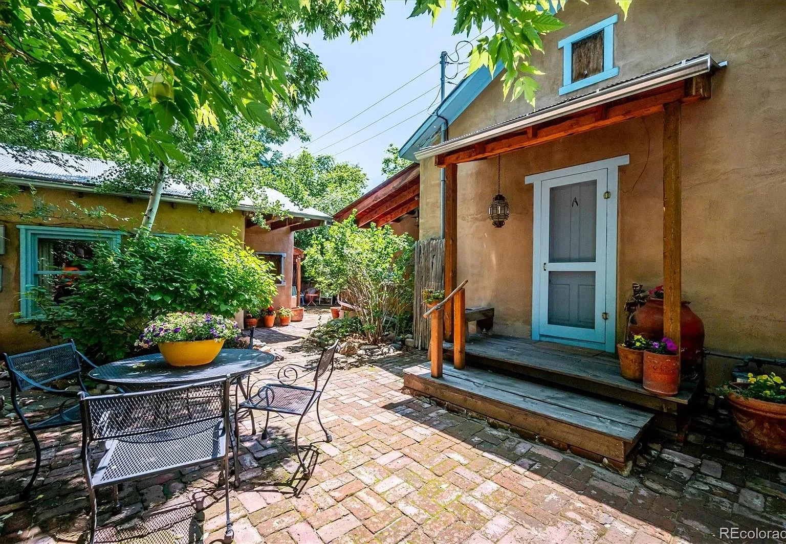 A metal patio table sits in a courtyard outside a Santa Fe style house.