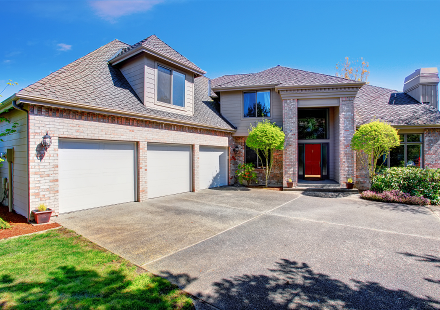 Front view of a modern house with a brick and gray exterior, three-car garage, and landscaped yard.