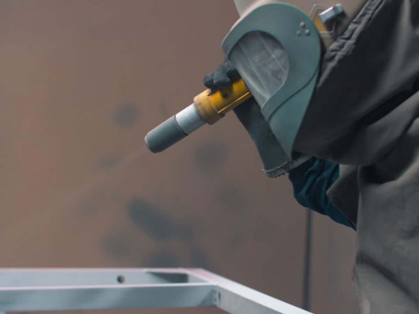 A person wearing gloves using a blowtorch to heat metal in a workshop.
