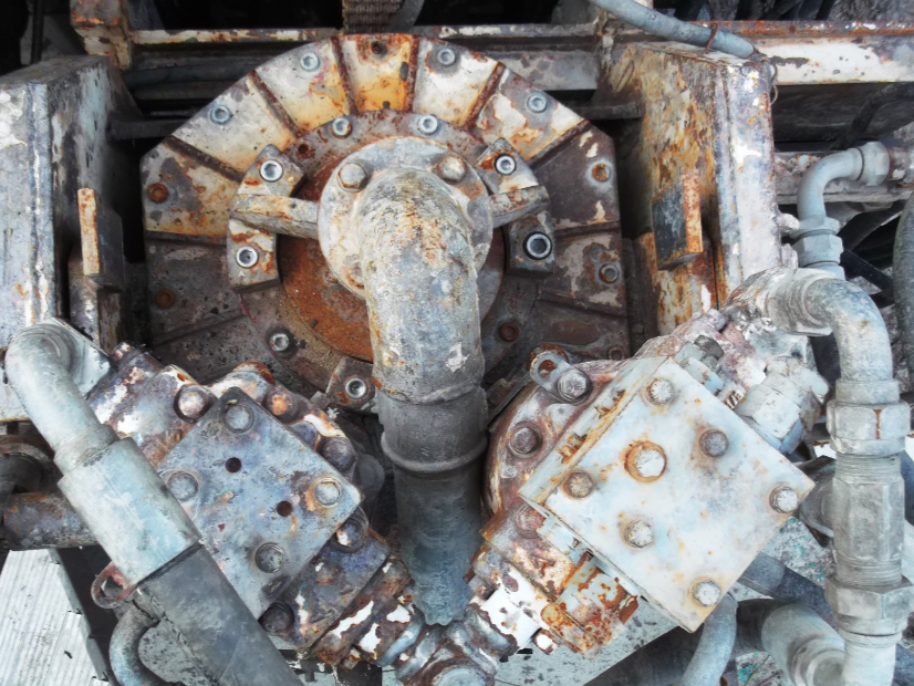 Close-up of a rusty, industrial machinery component with pipes and bolts.