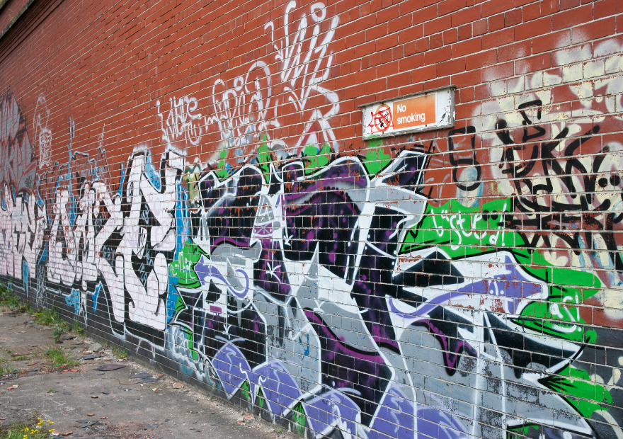 Colorful graffiti art on a brick wall next to a no smoking sign.