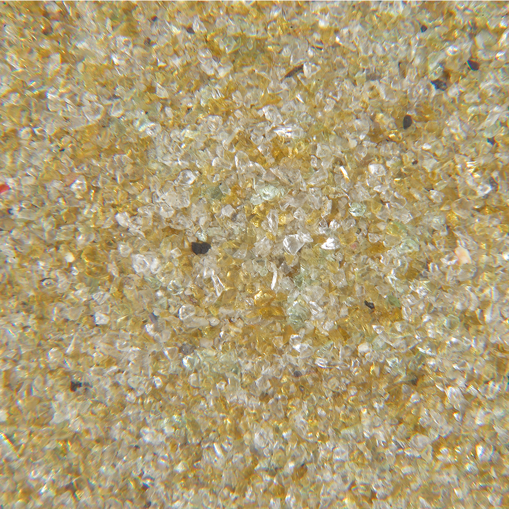 Close-up of fine golden yellow sand with small black and green particles.