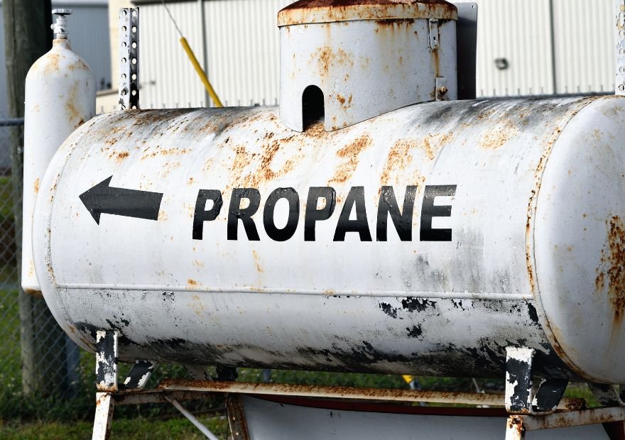 A rusty white propane tank with a black arrow pointing to the left and the word "PROPANE" in black letters, making it the perfect project for Ready Surface, a dustless blasting company serving North Texas.