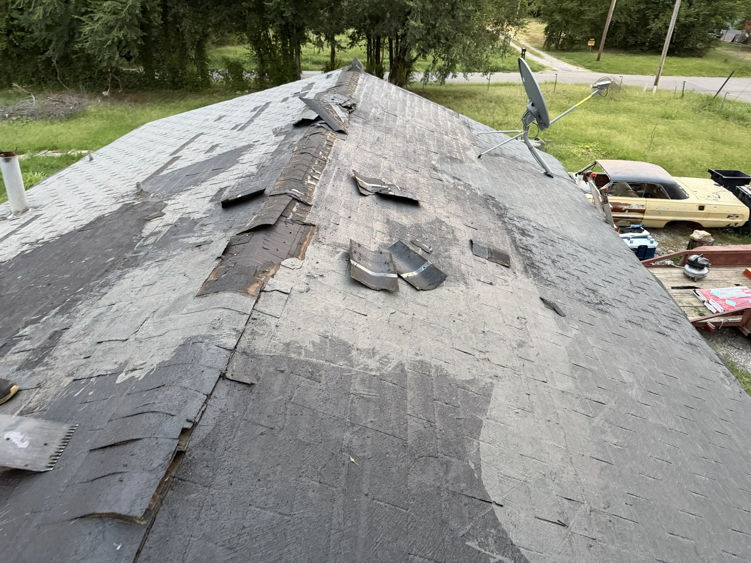 A roof with damaged and missing shingles.