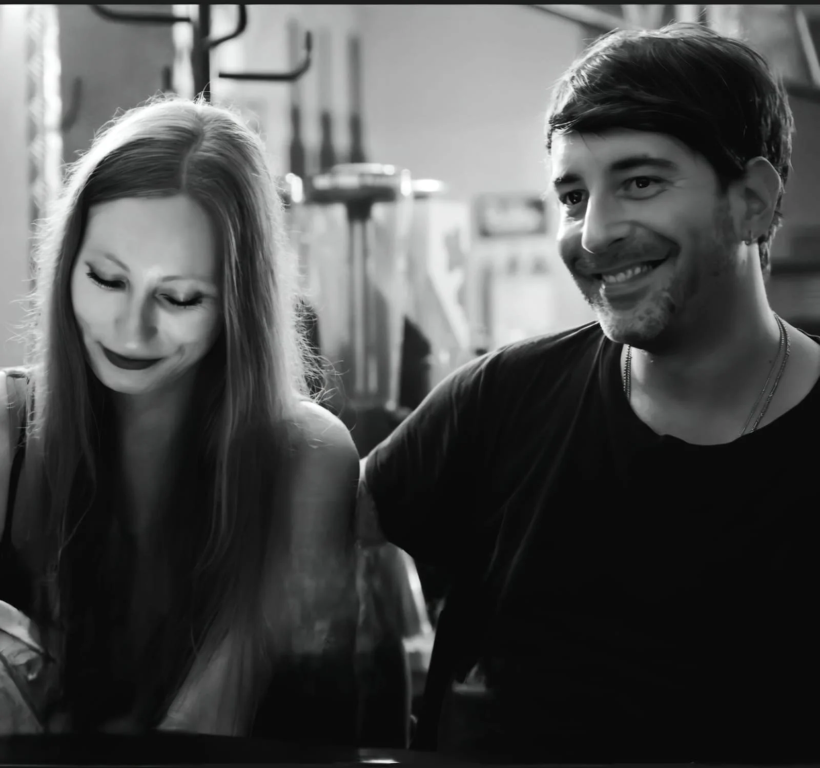 Schwarz-weiß-Foto eines lachenden Mannes und einer Frau, die in einem Raum sitzen, vermutlich in einer Kneipe oder einem Café.