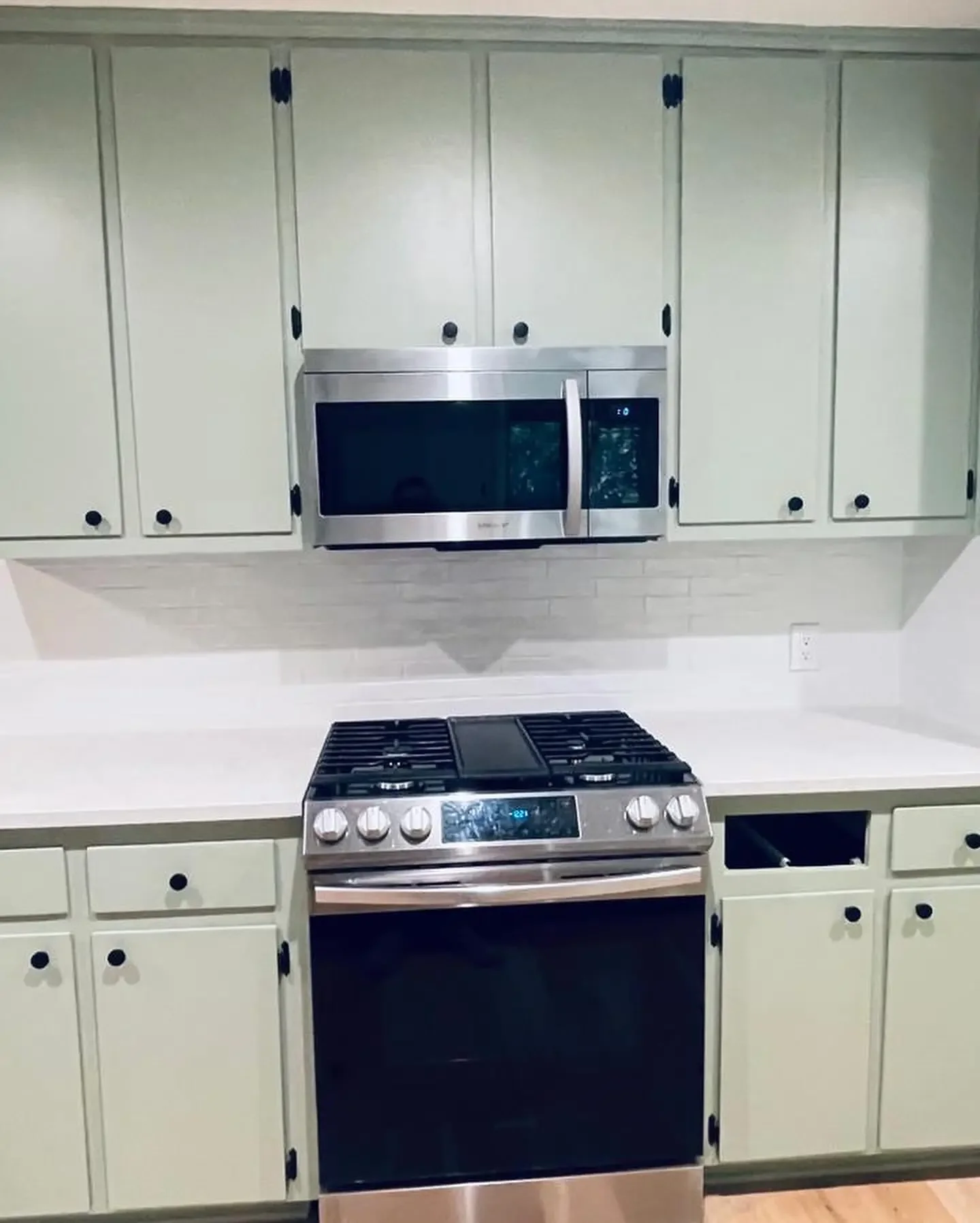 Kitchen with cream-colored cabinets, a stainless steel microwave above a stove, and a disconnected cabinet space.