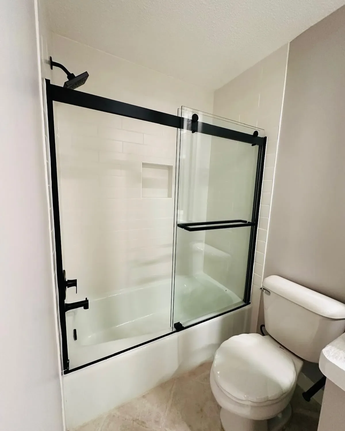 A modern bathroom with a bathtub enclosed by glass sliding doors, and a white toilet beside it.