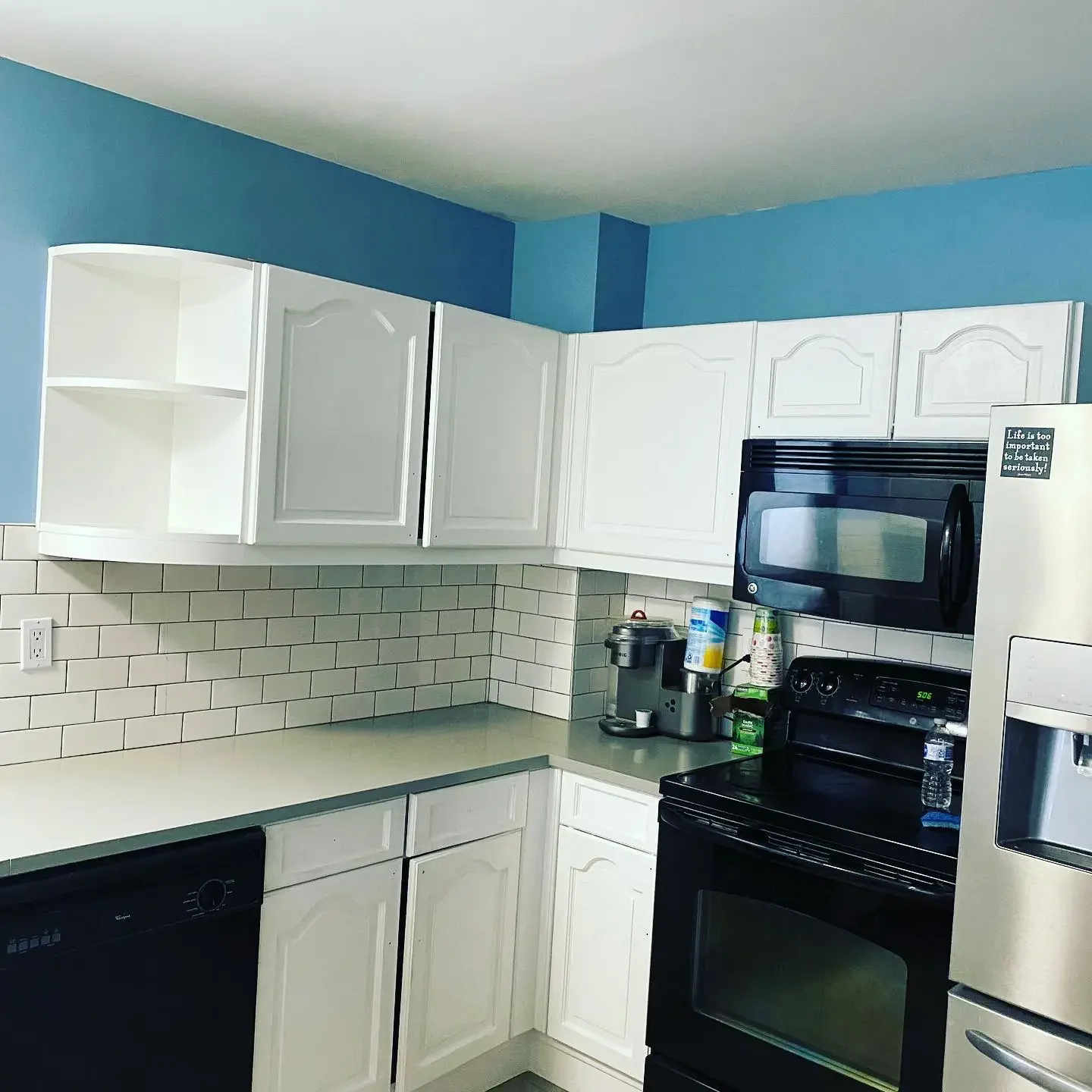 Kitchen with white cabinets, black stove, microwave, dishwasher, granite countertop, and blue walls