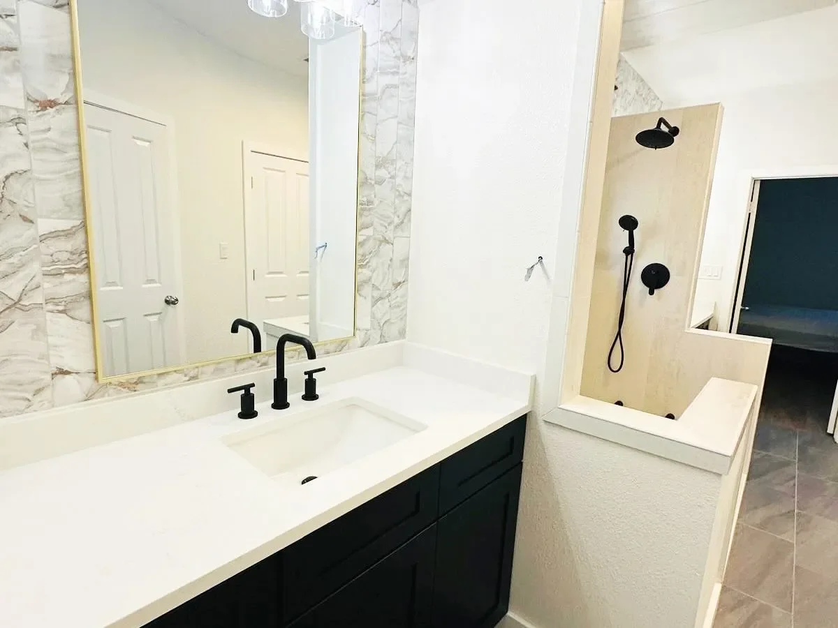 Bathroom with a white vanity, black faucet, large mirror, and a walk-in shower with black fixtures.