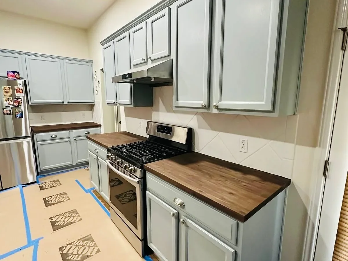 Kitchen with light gray cabinets, wooden countertops, stainless steel appliances, and a gas stove.
