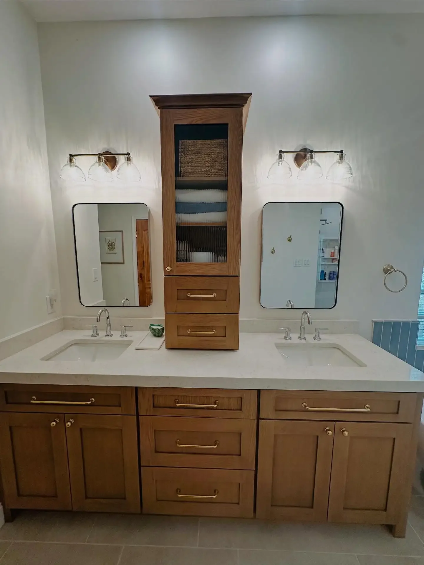 Bathroom vanity with two sinks, wooden cabinetry, and two mirrors with wall-mounted light fixtures above each mirror.