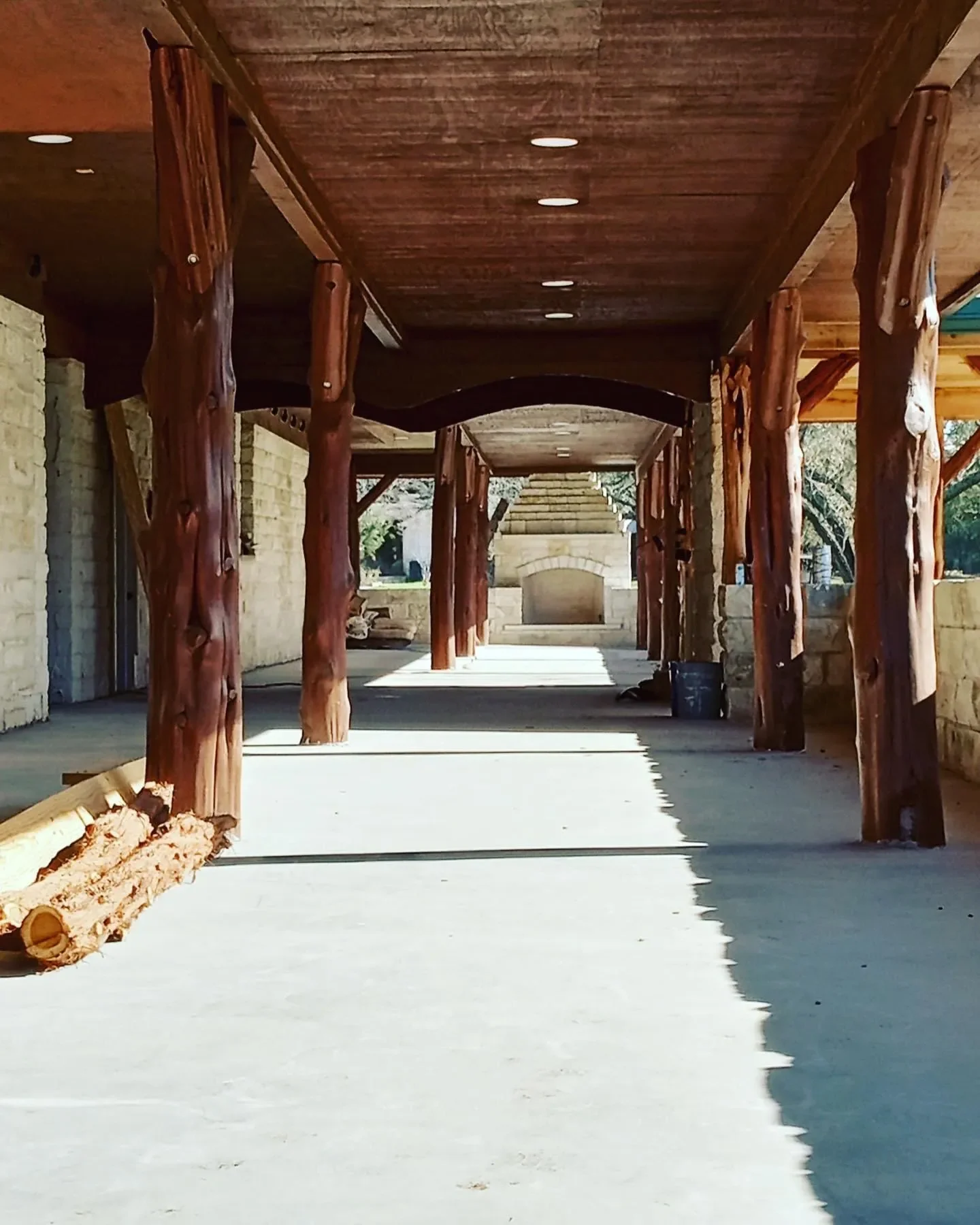 Construction site with wooden beams and stone walls, empty concrete floor, and stone steps in the background.