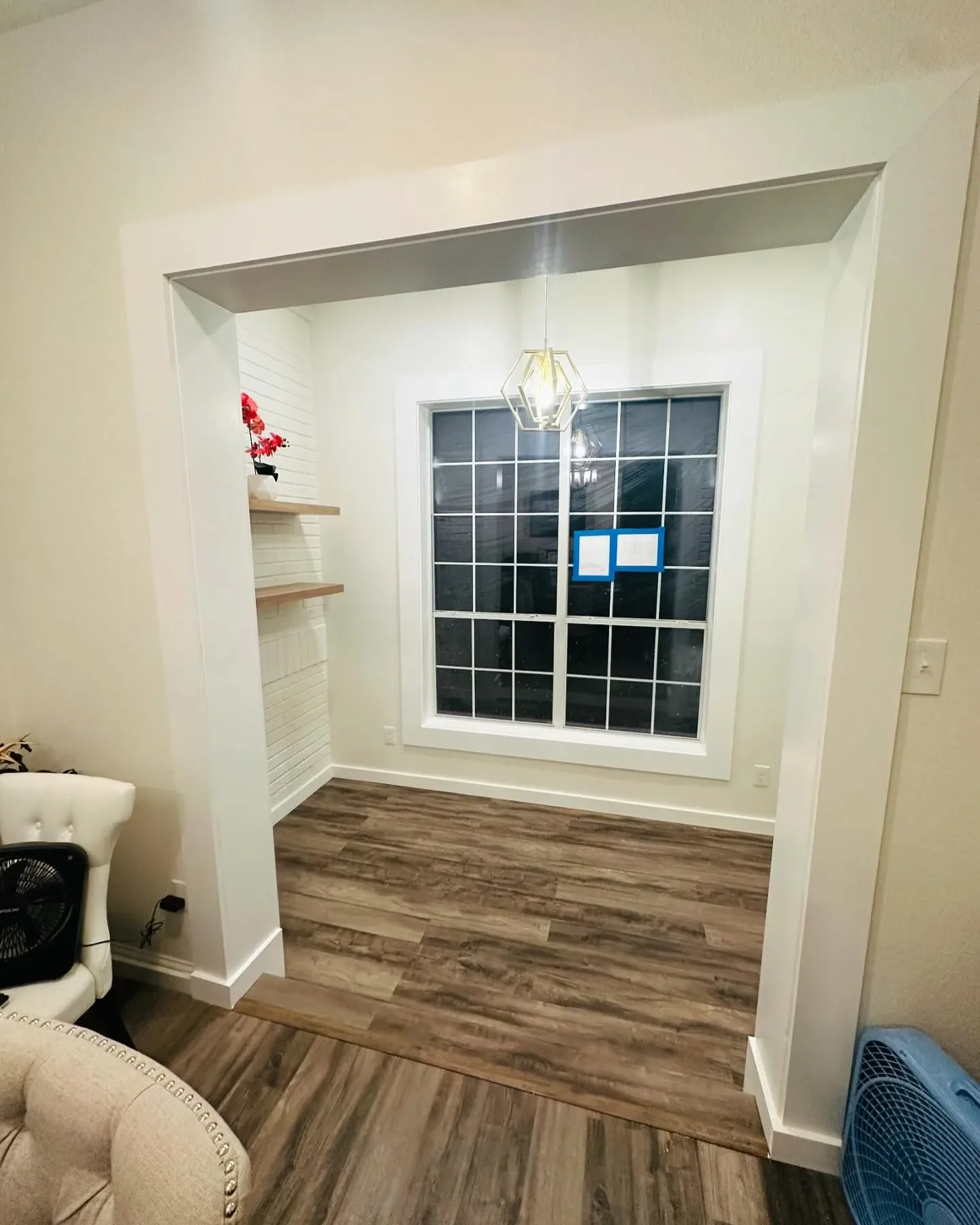 Empty dining nook with large window, wooden flooring, and modern light fixture.