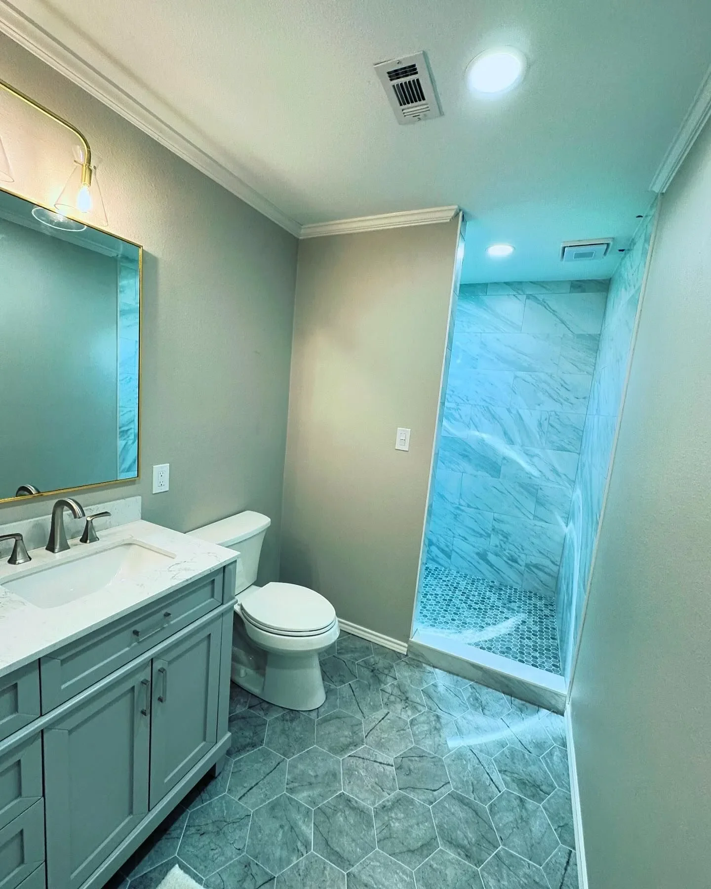 Bathroom featuring a vanity with a mirror, a toilet, and a walk-in shower with marble tiles and pebble floor.