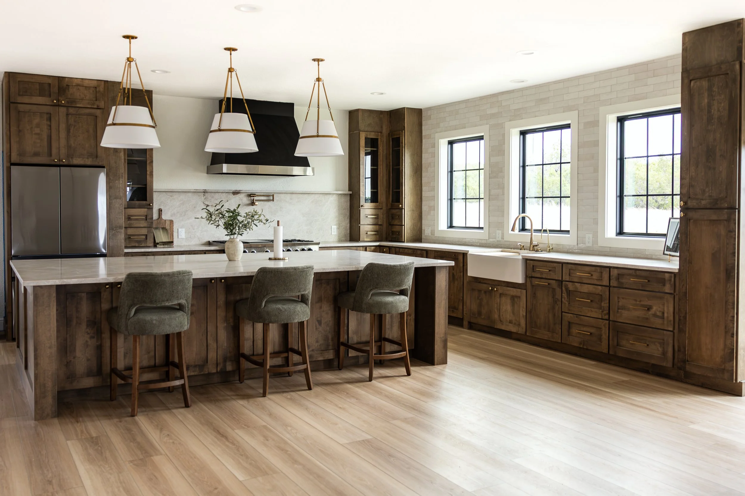 This custom kitchen remodel features rich stained wood cabinetry, a large island, quartz countertops, a farmhouse sink, custom storage solutions, and elegant lighting. Designed for both beauty and functionality, this luxury kitchen renovation creates