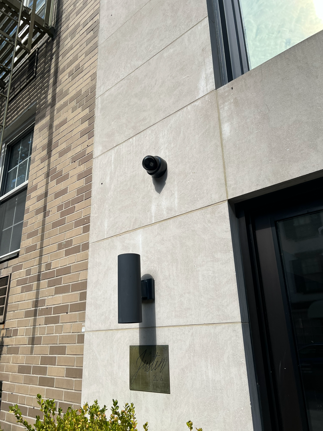 Vandal-resistant outdoor security camera mounted on an apartment building brick facade in NYC.