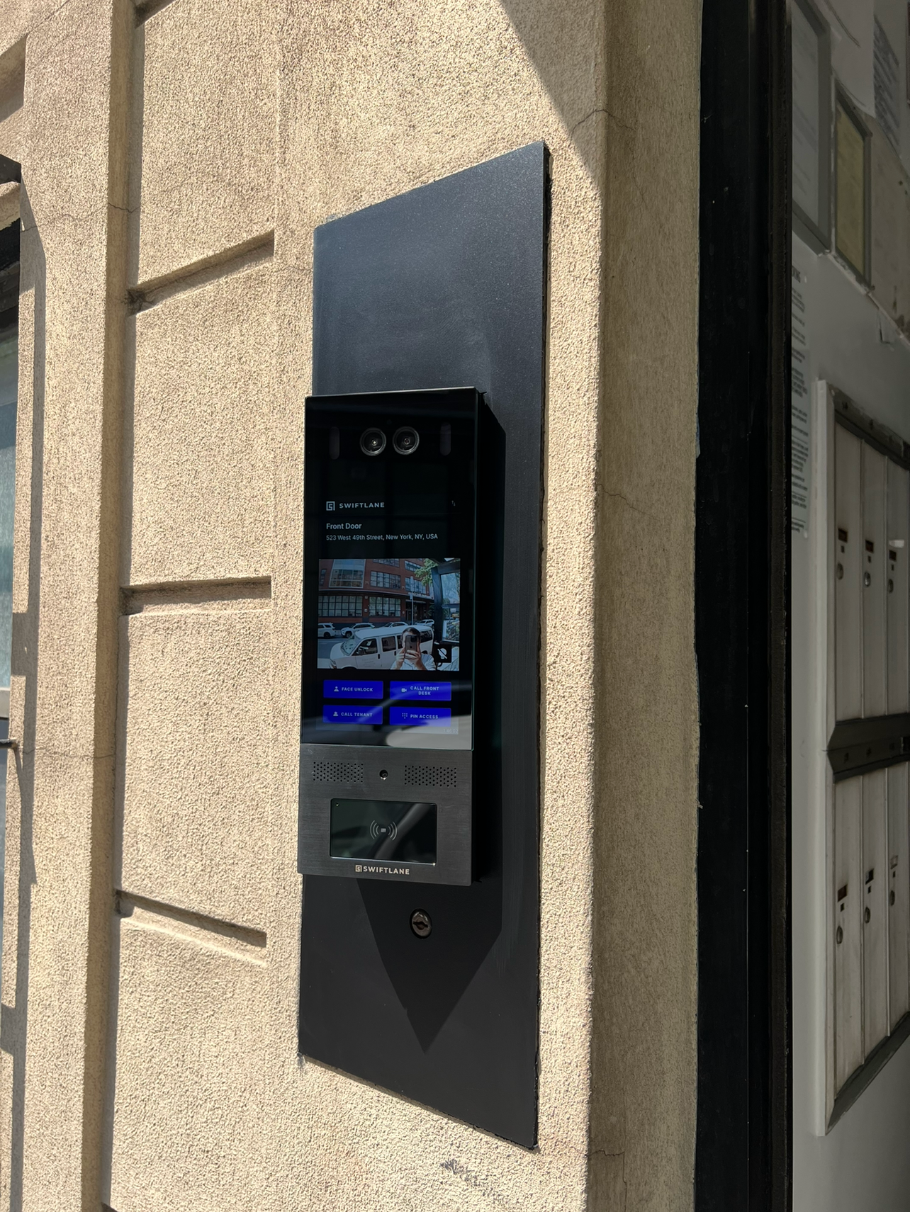 Swiftlane touchscreen video intercom system and visitor management device installed at a property entrance.