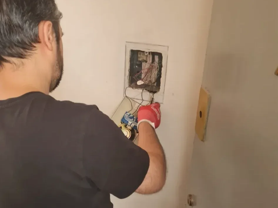 Man repairing or installing electrical wiring into an electrical box on the wall.