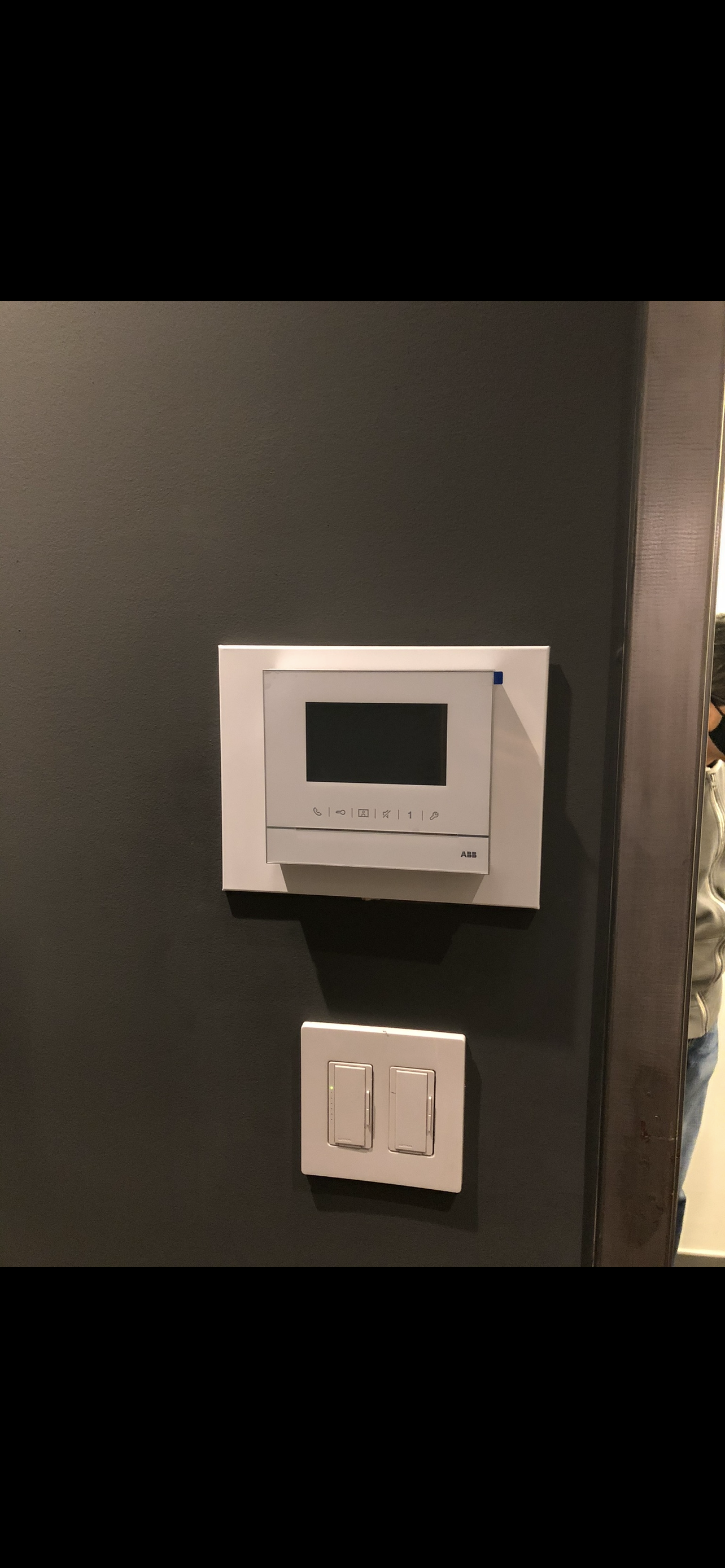 A black wall with an electronic control panel and a double switch.