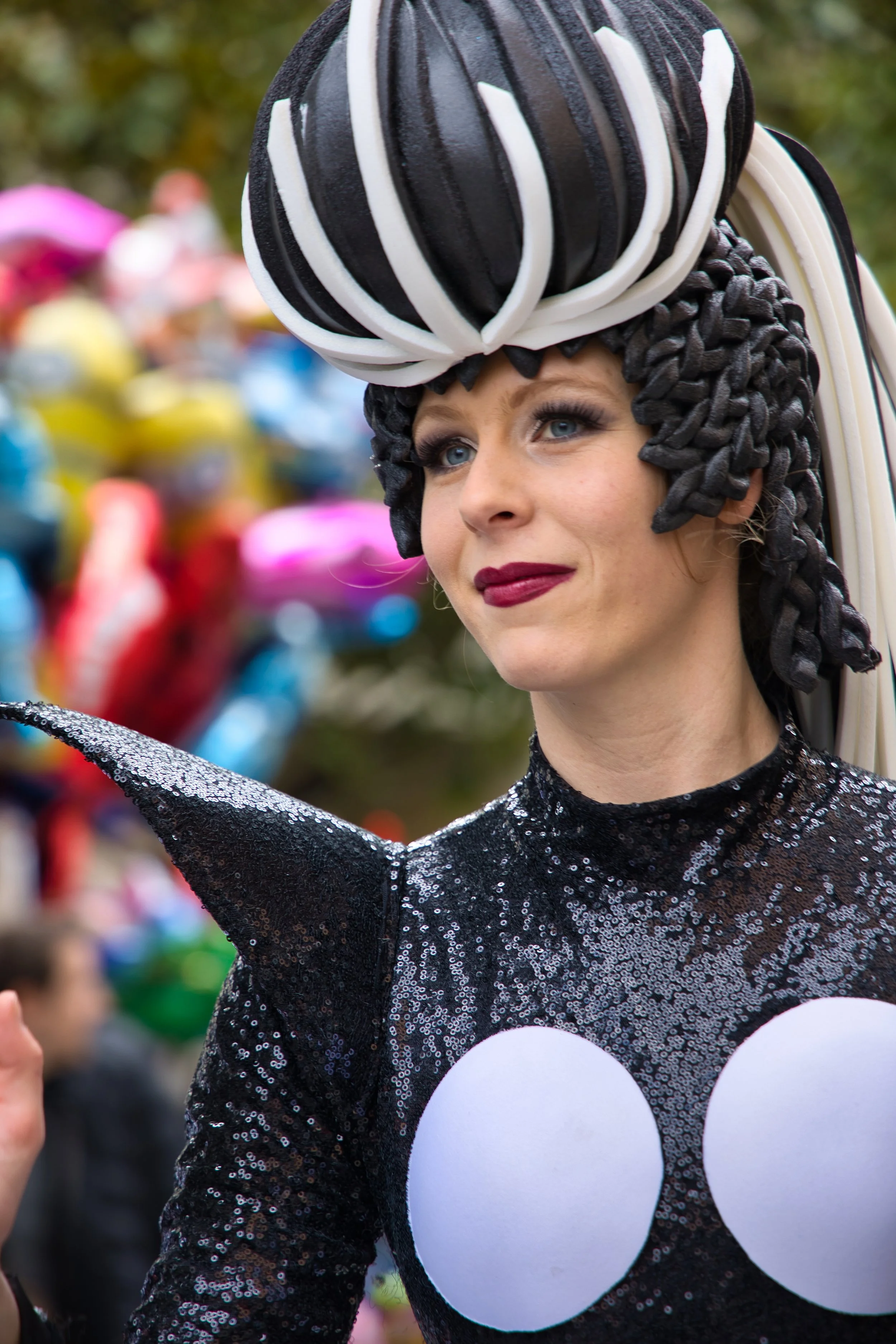 Une femme portant un costume de personnage de dessin animé, avec une tête en forme de ballon et des détails en forme de seins, lors du carnaval de Thiais