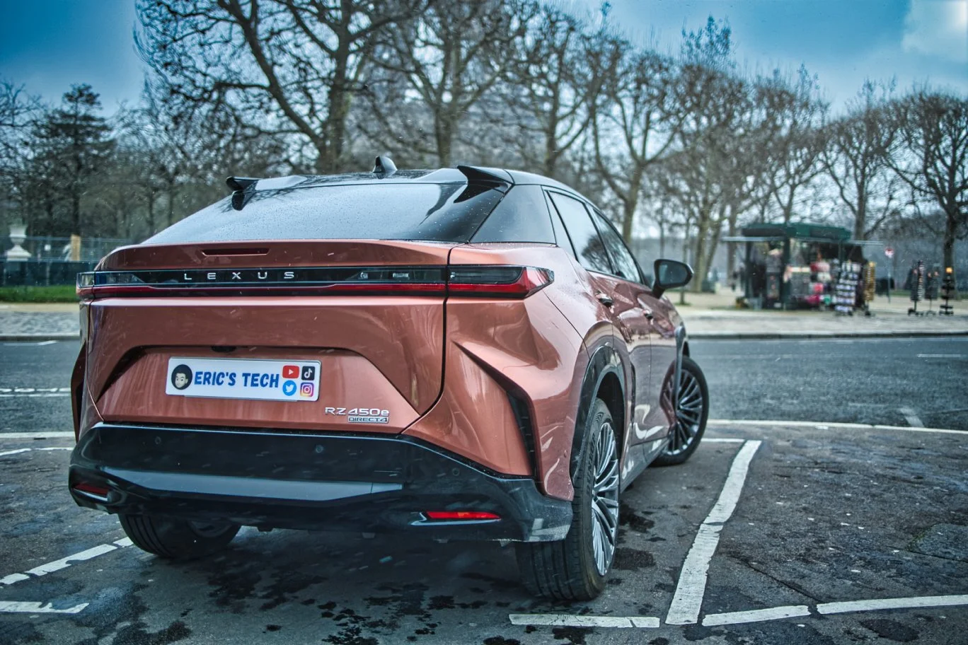 Voiture électrique Lexus RZ 450e orange stationnée dans un parking vide, vue arrière.