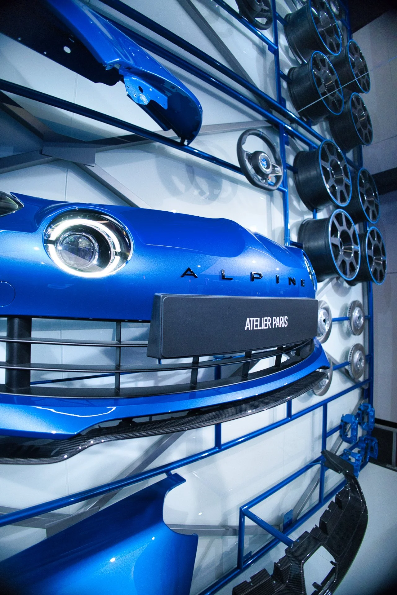 Pièce de voiture en bleu, composants automobiles et jantes sur un mur d'exposition à l'atelier Alpine à Paris