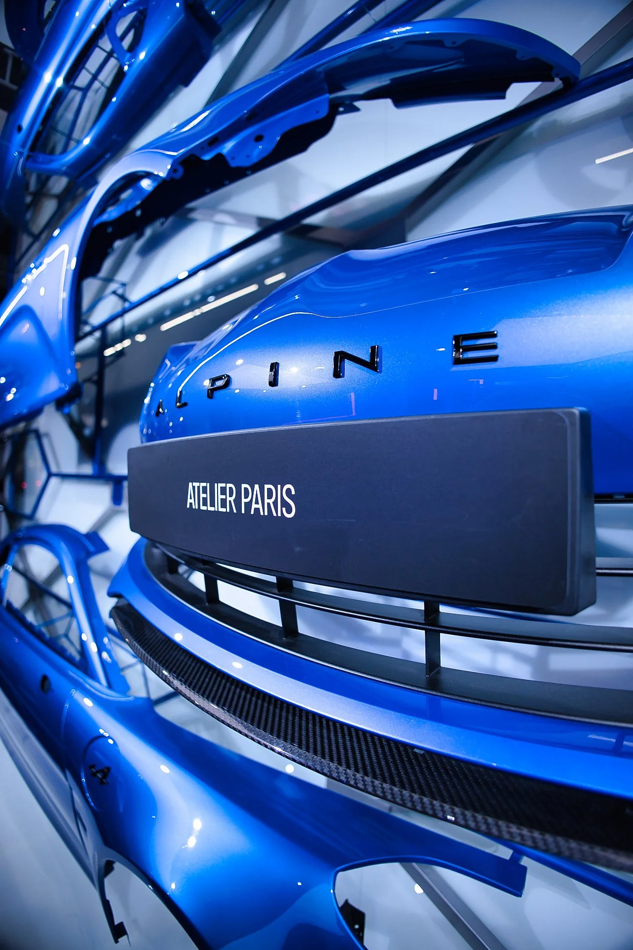 Mise en valeur de pièces de voiture bleues dans un atelier parisien, avec une plaque indiquant 'ATELIER PARIS'.