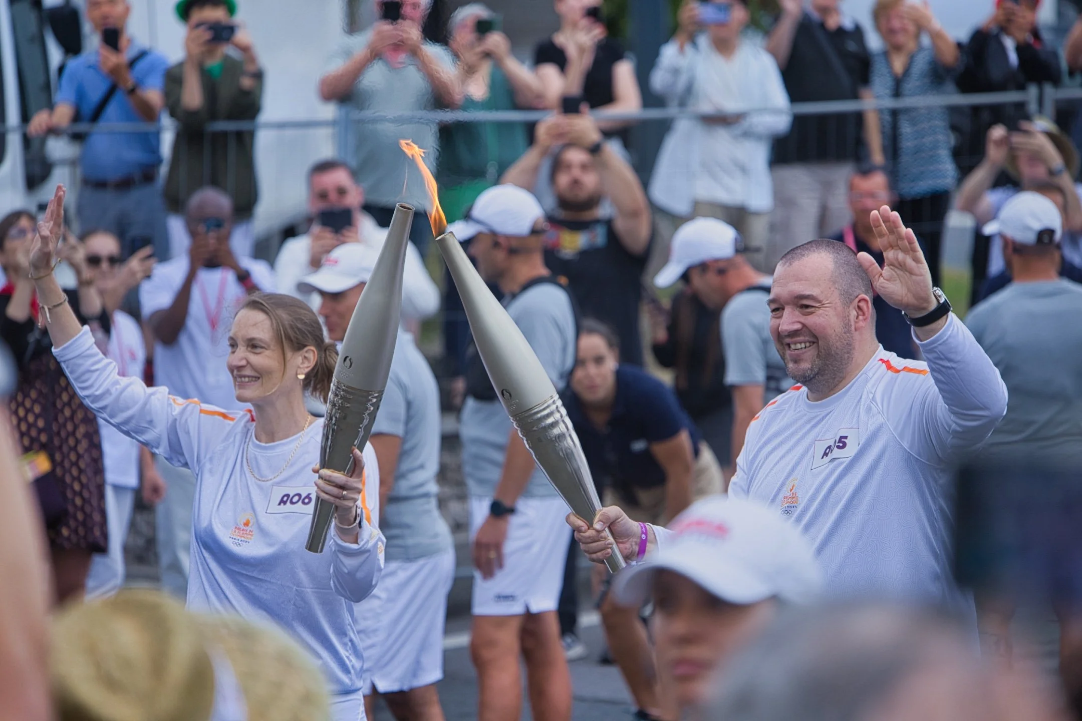 Deux personnes applaudissent en tenant des torches de flamme lors du passage de la flamme olympique au marché de Rungis