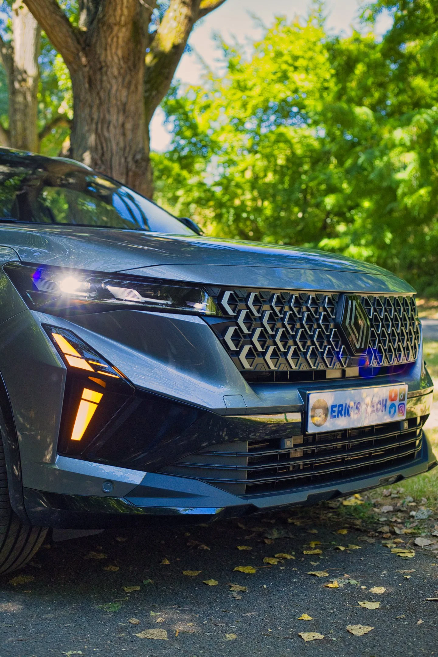 Renault Austral e-tech 200 garée sous un arbre avec un fond de feuillage vert 