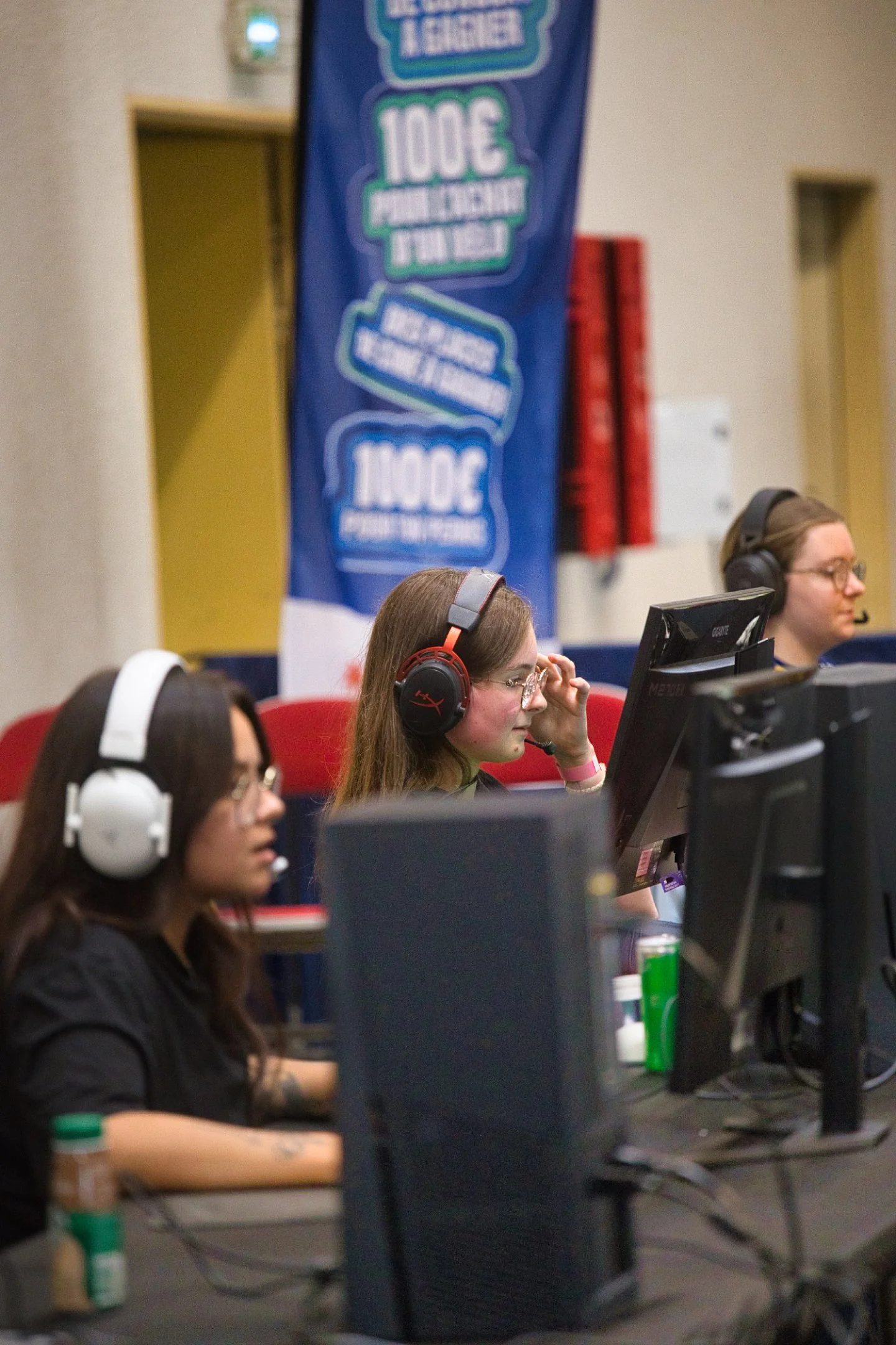 Trois personnes jouent à un jeu vidéo en utilisant des casques audio, assises devant des ordinateurs lors de l'évènement Gaming Théodasium 2025 à Thiais