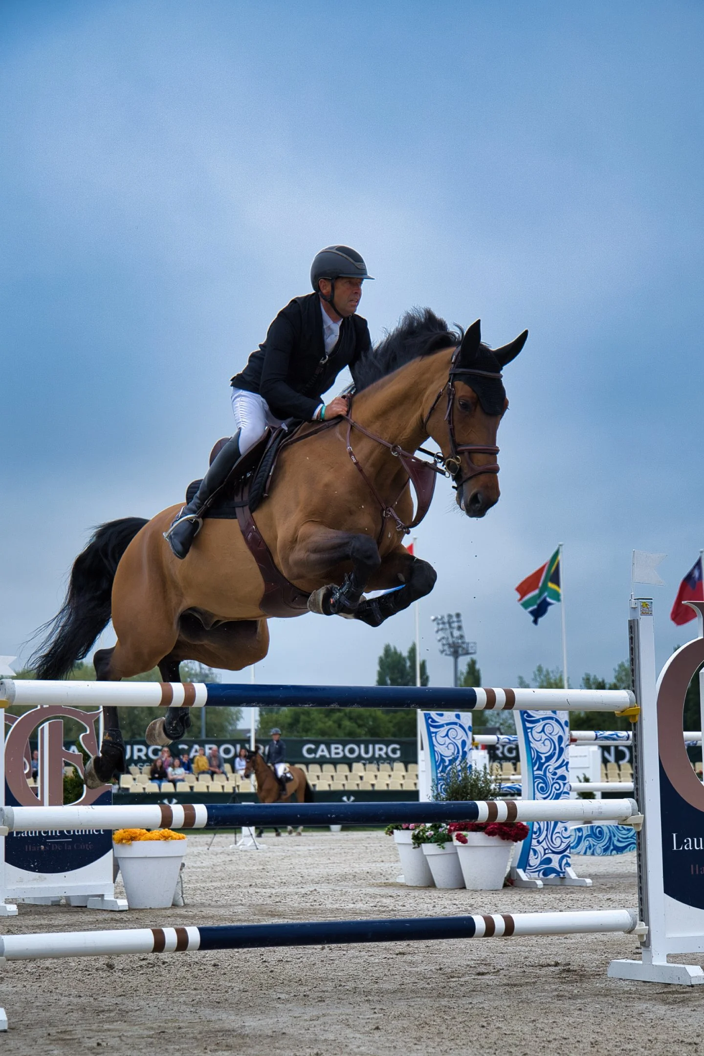 Un cavalier en tenue de compétition sautant une clôture lors d'une épreuve de saut d'obstacles.